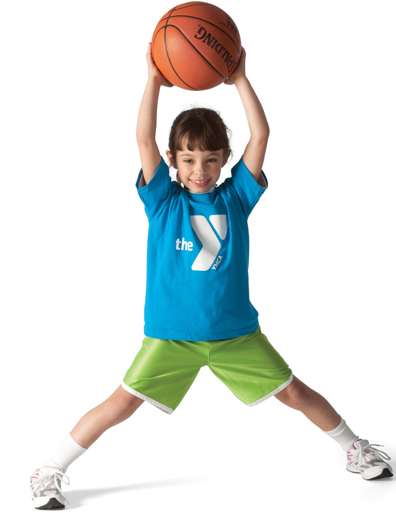 Girl holding basketball jumping in air.