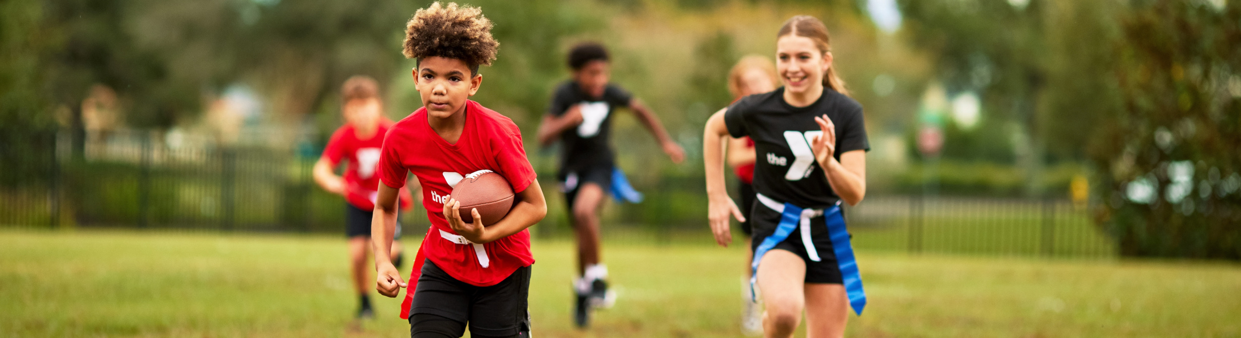 A child holding a football running towards the end zone.