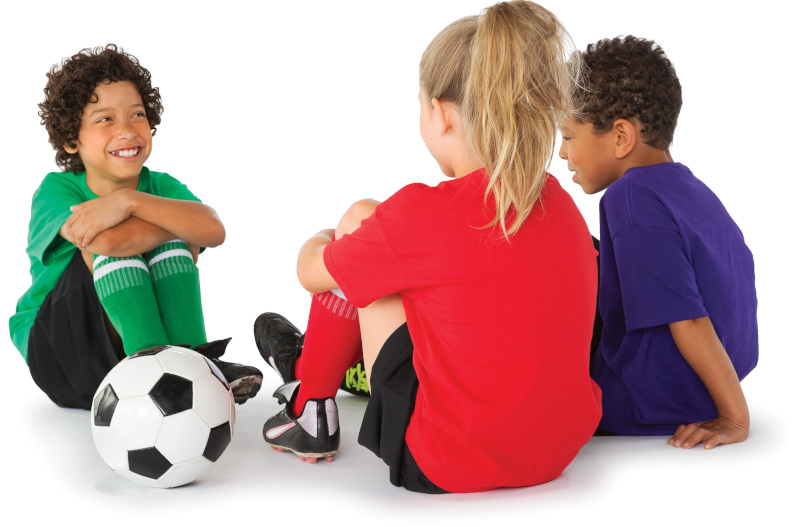 Three children in soccer uniforms chatting near a soccer ball.